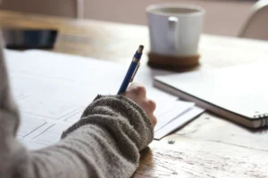 Student writing notes while studying to stay motivated during long academic projects and research assignments.