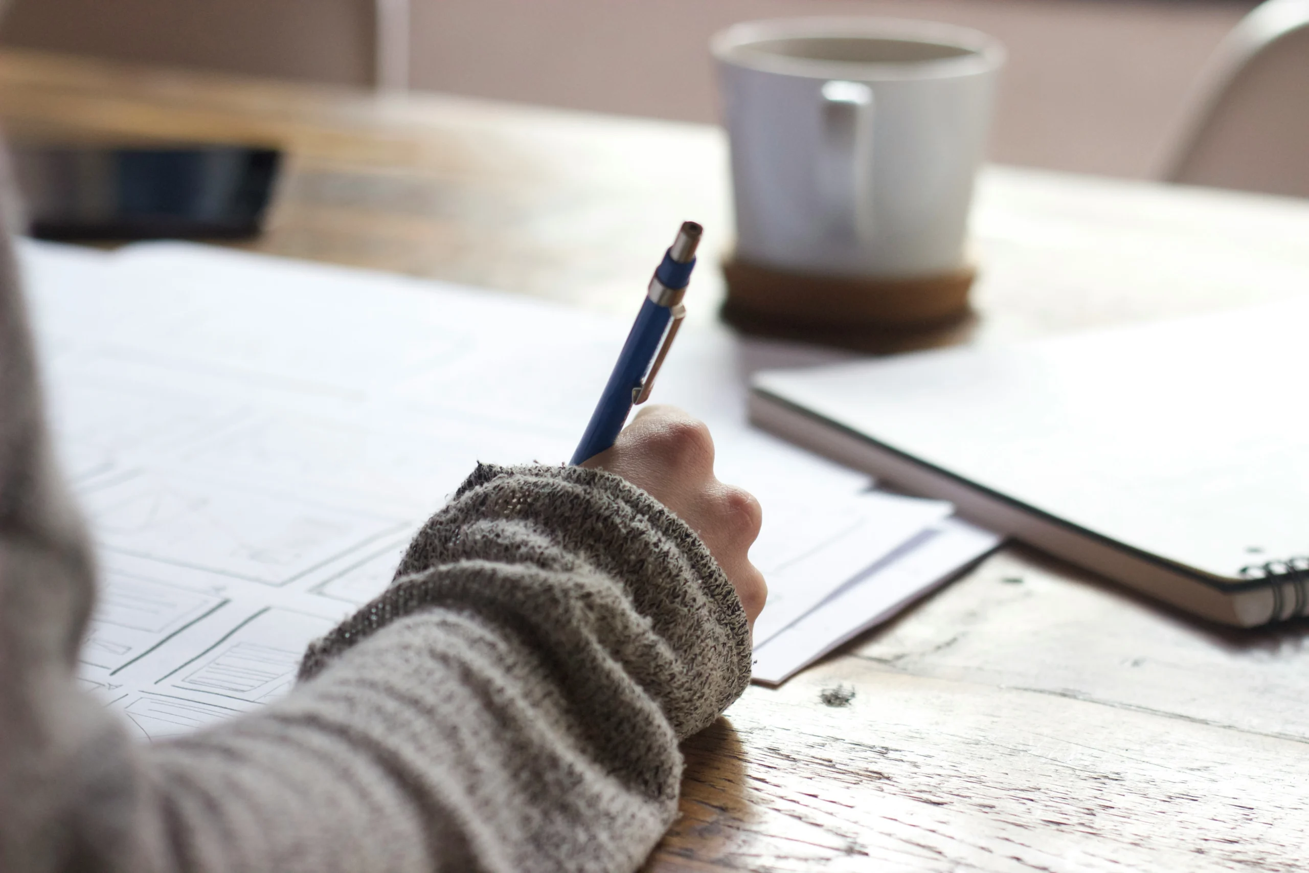 Student writing notes while studying to stay motivated during long academic projects and research assignments.