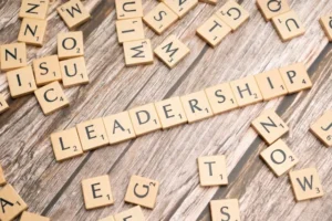 Scrabble tiles spelling Leadership on a wooden table, representing leadership skills, personal development, and student academic success.